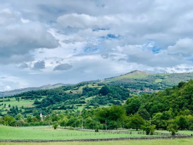 Dağları ve bulutlu gökyüzü olan güzel bir manzara.