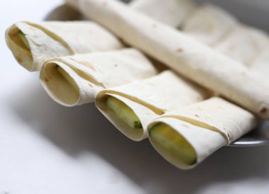 Lavaş rulosu, kırmızı somon dolması ve erimiş peynirle tatlandırılmış yeşil sulu salatalık içine dilimlenmiş. mağaza afişleri ve yemek kitabı kapakları için