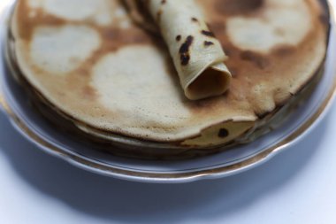 Bir sürü krep ve krep üzerine beyaz bir tabakta uzanır. Mutfak masasında altın kenarlı bir tabakta. Yemek kitapları ve not defterleri için.