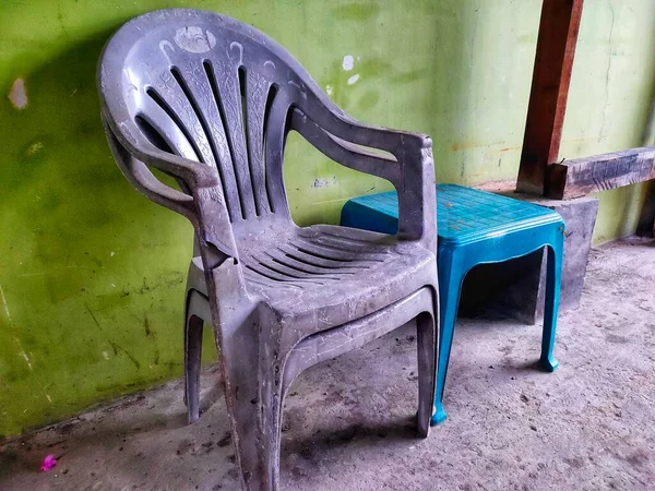 Gray plastic chairs and green plastic tables are located on the terrace of the house.