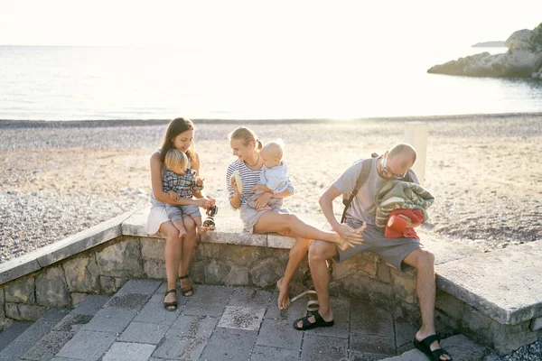 Mothers with children in their arms sit on the curb of the beach. High quality photo