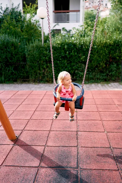 Smiling little girl swinging on a chain swing. High quality photo