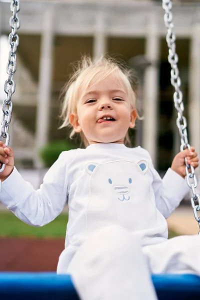 Little girl in a tracksuit on a chain swing. High quality photo