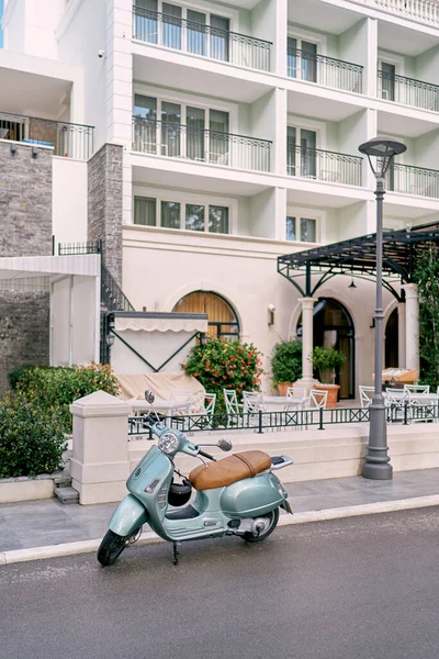 Green motor scooter parked near a multi-storey building. High quality photo