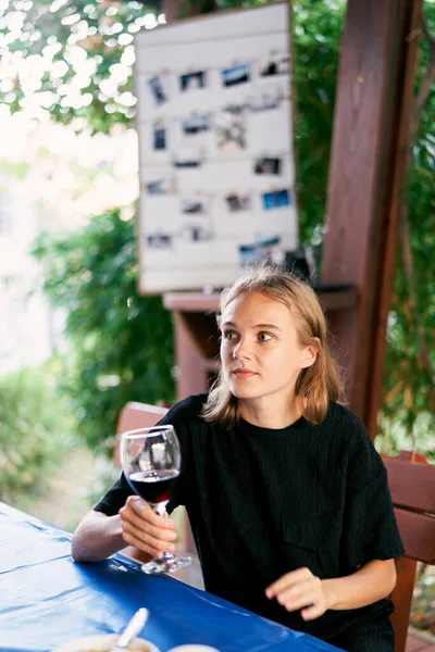 一个手里拿着酒杯的年轻女人坐在桌旁 高质量的照片 — 图库照片