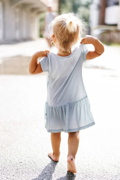 Küçük kız su birikintilerinde yalın ayak yürüyor. Arkadan bak. Yüksek kalite fotoğraf