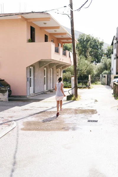 Young woman jumping over a puddle near the house. High quality photo