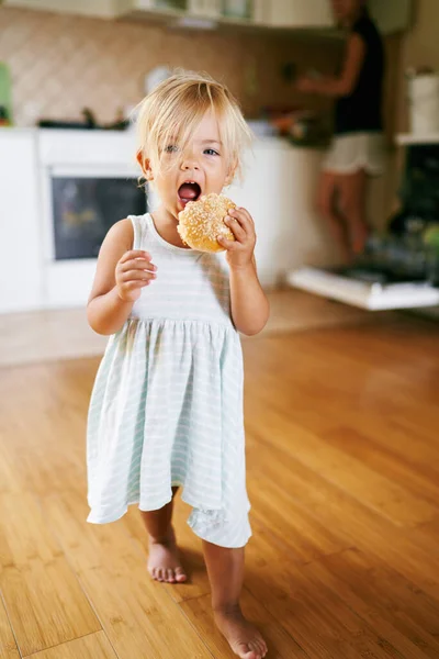 Küçük kız mutfakta yürüyor ve çörek yiyor. Yüksek kalite fotoğraf