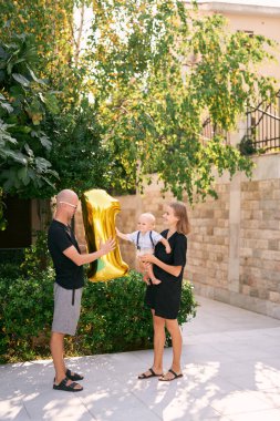 Annem, elinde şişme bir numarayla babamın yanında dururken kucağında küçük bir çocuk tutuyor. Yüksek kalite fotoğraf