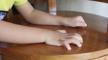 Tanımlanamayan bir çocuk elleri sandalyeyi tutuyor ve hareket ettiriyor.
