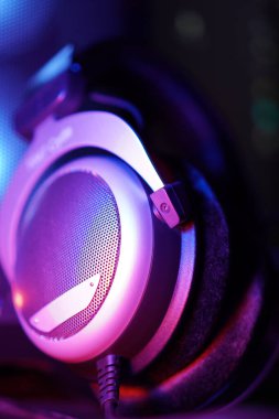 A vertical closeup shot of headphones Illuminated by blue and purple light shot with a shallow depth of field