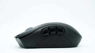 Black modern gaming mouse with six side buttons, isolated on a white background, sitting on a white surface. Photographed from the side.