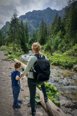 Anne ve oğul dağlarda güzel bir manzaraya bakıyorlar.