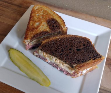 Marble Rye üzerinde bir Deli Ruben Kare beyaz tabakta bir turşuyla