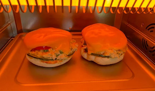 Tuna Melt on a English Muffin with American Cheese Melting on top cooking in a toaster oven