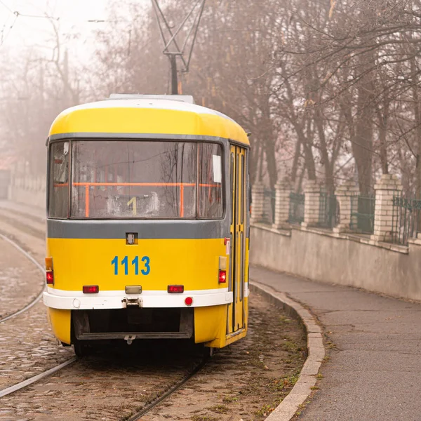 yellow tram rides through the foggy city. alley.paving stones