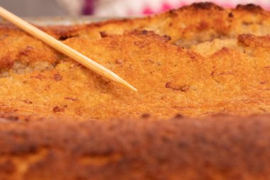 Pişip pişmediğini test etmek için yeni pişmiş bir kekin üzerinde duran şişin yakın çekimi.. 