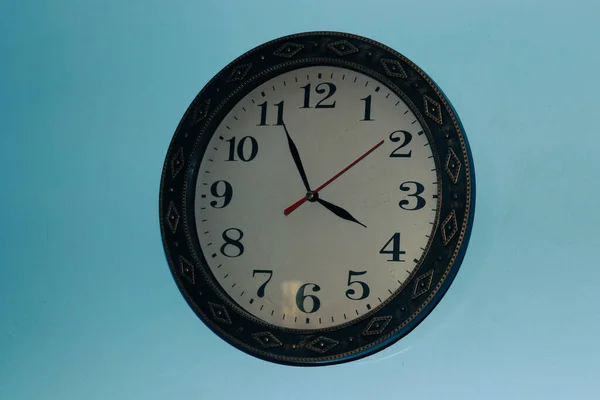 The old clock design is found on a blue wall; the frame of the clock is made from wood