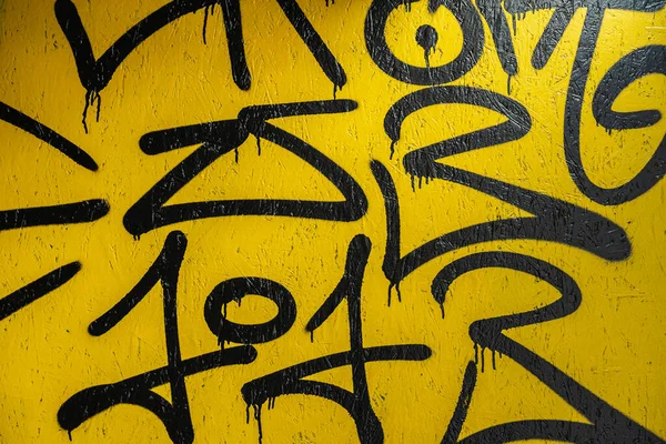 Abstraktní fragment kreativní černé čmáranice na žlutě natřenou betonovou stěnu. Moderní pozadí Royalty Free Stock Fotografie