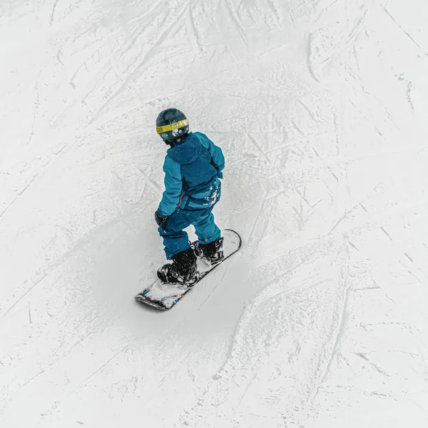 Zadní pohled na mladého snowboardistu jedoucího na sjezdovce. Zimní venkovní volný čas, sport — Stock fotografie