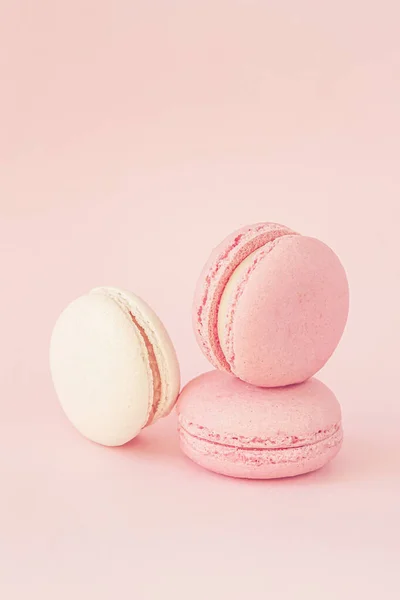 Macarrones coloridos sobre fondo de melocotón rosa pastel, concepto romántico postre dulce —  Fotos de Stock