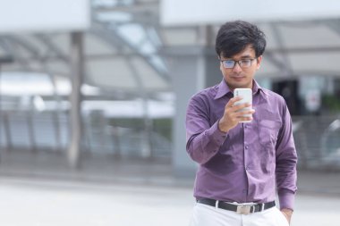 Sweating young asian businessman looking at messages on cellphone