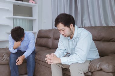 Genç adam ve arkadaşı oturma odasında kanepede oturuyorlar.