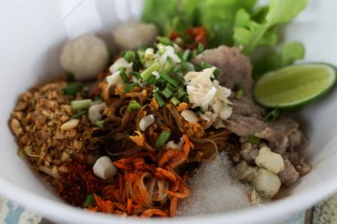 Closeup Spicy TOM YAM Pork Noodles Soup with Pork Balls, chilly pasted and lime juice  Noodles in Thai spicy tom yum soup with pork.