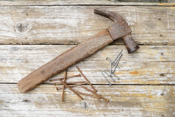 Hammer and nails on wooden background, wood and rust head iron hammer lying on wooden board with outdoor workshop.