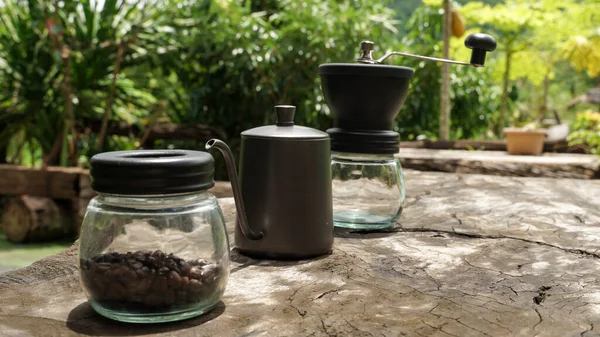 The drip coffee set includes coffee beans, drip kettle and a coffee grinder.  place on wooden table.