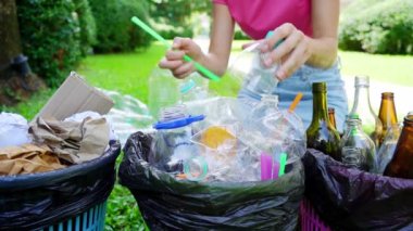 Young woman sorting plastik trash in the yard of the house.