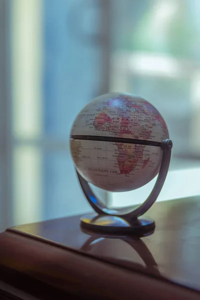 globe and magnifying glass on wooden table