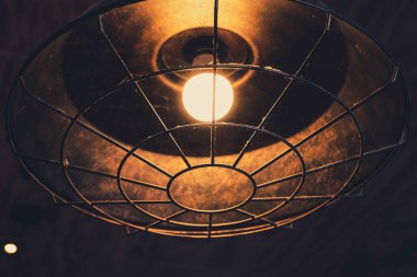 An old style lamp with a grunge metal cover hang in coffee shop look vintage