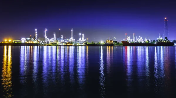 Cityscape at night with a lighting reflection in a river. Oil refinery industrial of thailand.