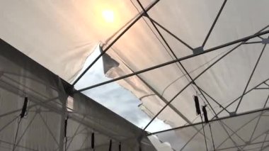 Güçlü rüzgarlarla kırılan plastik seranın yatay videosu.