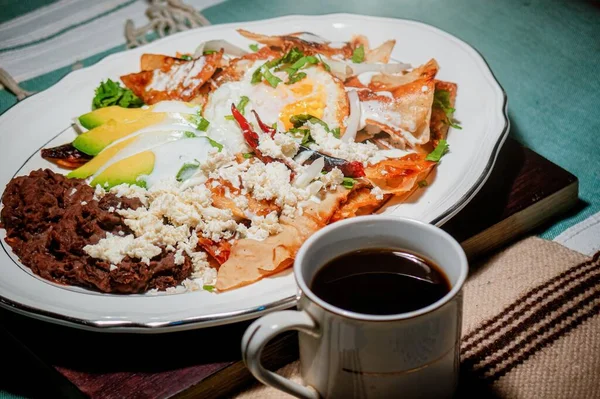 Kırmızı soslu bir Chilaquiles Meksika yemeği, peynir, krema, kırmızı biber ve kahve.