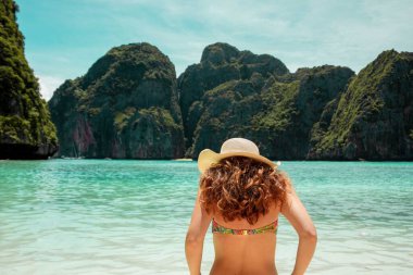 Girl in swimsuit and hat on Phi Phi beach in Thailand, summer, tropical landscape, sea and green islands