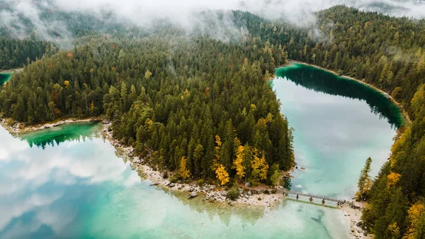 Autumn in the Bavarian mountains, Germany. Alps landscape with lake, bridge, clouds, forest, coast and turquoise water. View from above. Aerial drone outdoor photo.