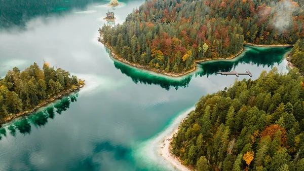 Autumn in the Bavarian mountains, Germany. Alps landscape with lake, clouds, forest, coast and turquoise water. View from above. Aerial drone outdoor photo.