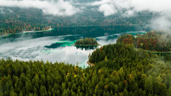 Autumn in the Bavarian mountains, Germany. Alps landscape with lake, clouds, forest, coast and turquoise water. View from above. Aerial drone outdoor photo.