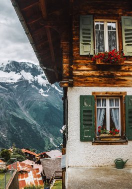 Lauterbrunnen, Switzerland, Jungfrau. Swiss Alps. Cozy small village in mountains. House with window traditional shutters, flower boxes and watering can. Beautiful landscape, Europe.