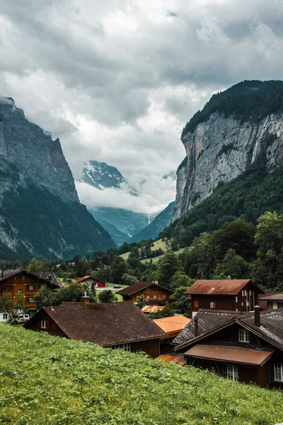 Lauterbrunnen valley, Switzerland. Swiss Alps. Cozy small village in mountains. Forest, rocks, clouds and green meadows. Beautiful landscape, Europe. Wooden houses, traditional chalet roofs.