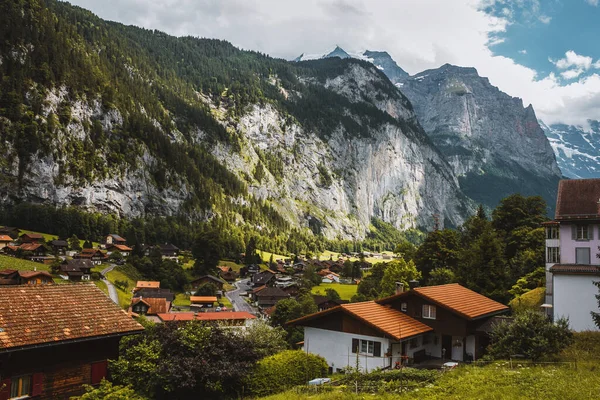 Lauterbrunnen valley, Switzerland. Swiss Alps. Cozy small village in mountains. Forest, rocks, clouds and green meadows. Beautiful landscape, Europe. Wooden houses, traditional chalet roofs.