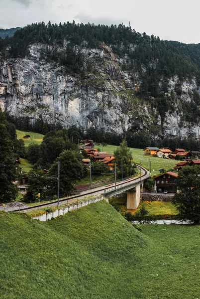 Lauterbrunnen valley, Switzerland. Swiss Alps. Cozy small village in mountains. Forest, rocks and clouds. Beautiful landscape, Europe. Traditional wooden houses. Railway Jungfraujoch.