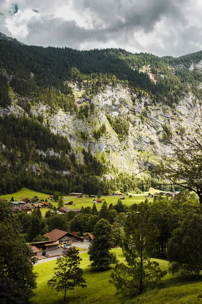 Lauterbrunnen valley, Switzerland. Swiss Alps. Cozy small village in mountains. Forest, rocks, clouds and green meadows. Beautiful landscape, Europe. Wooden houses, traditional chalet roofs.