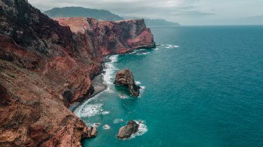 Atlantic ocean coastline with red cliffs, rocks, turquoise waves and sea foam. Madeira island, Portugal. Breathtaking, scenery landscape. High quality photo