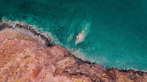 Atlantic ocean coastline with red cliffs, rocks, turquoise waves and sea foam. Madeira island, Portugal. Breathtaking, scenery landscape. High quality photo