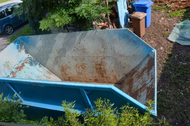 Garaj yolunda büyük boş bir konteynır duruyor.