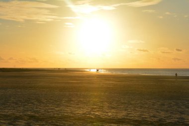 Portakal rengi gün batımı denizin üzerinde kumlu bir sahilde