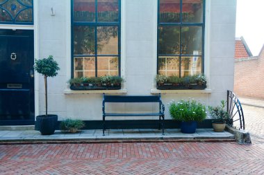 Hollanda 'nın Zeeland kentindeki eski ZIERIKZEE kasabasında bir bank ve çiçeklerle tipik bir ev.